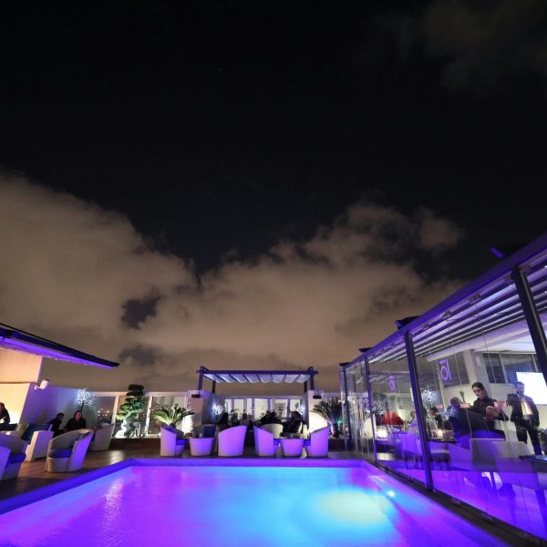 pexels-photo-2105327-2105327 A vibrant rooftop lounge with a glowing pool under a starlit night sky, perfect for relaxation.